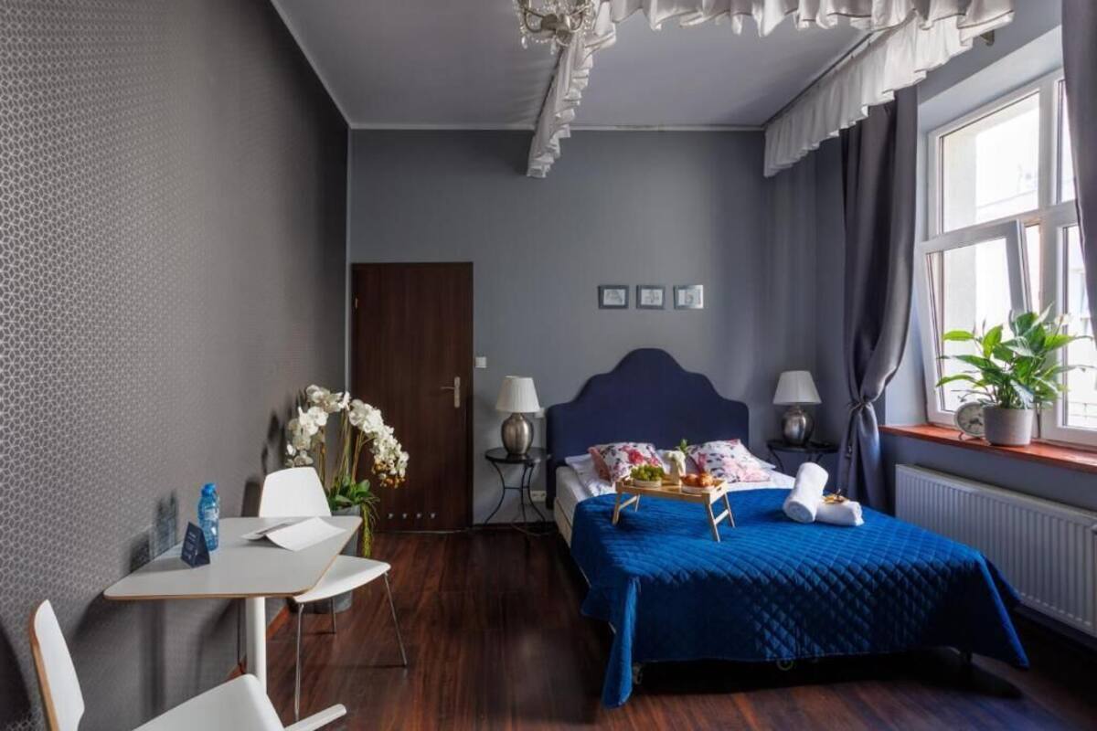 Ein Hotelzimmer mit Bett, Nachttisch, Sessel, Schreibtisch und einem Fenster mit Vorhängen.