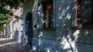 Edifici amb porta verda, finestres arquejades i un rètol que indica un negoci.