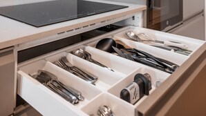 A modern kitchen with a built-in oven and microwave, a stainless steel induction cooktop, and a drawer organizer with utensils. - C1 Fully Renovated & Modern | Central | A/C (Lisboa ciudad)