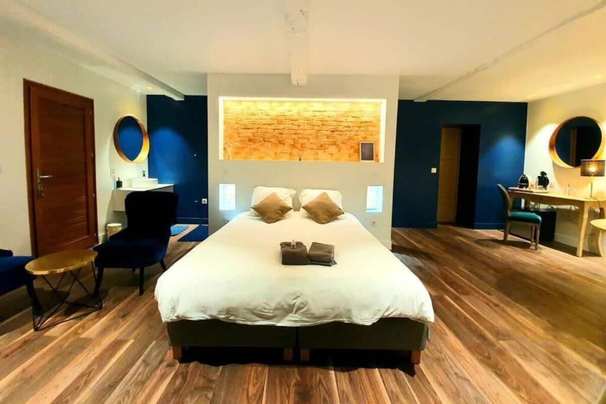A modern hotel room with a large bed, a desk, and a seating area.