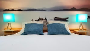 A bed with a view of a calm lake and mountains in the distance, a wooden dock, and two lamps on either side. - les granges de jules (Lafitte-Vigordanne)