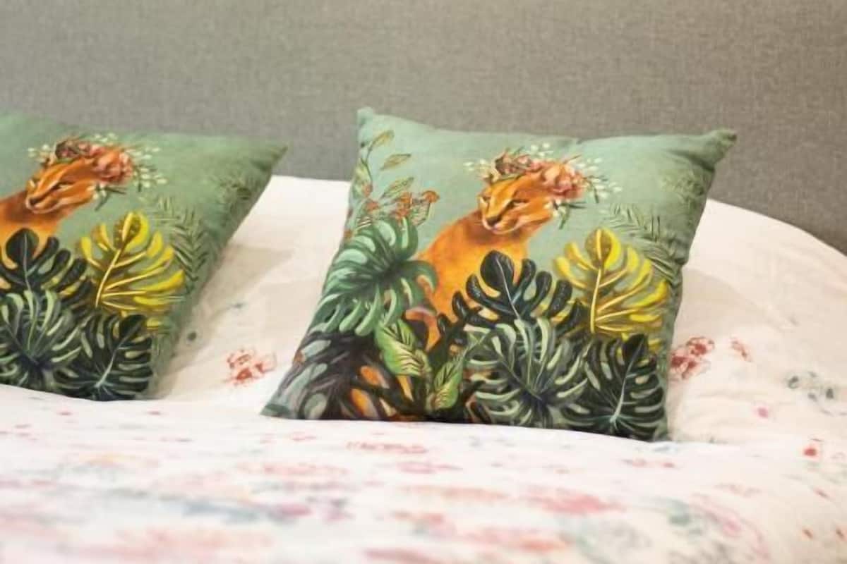 A bed with a floral bedspread and two pillows with a fox and plant design.