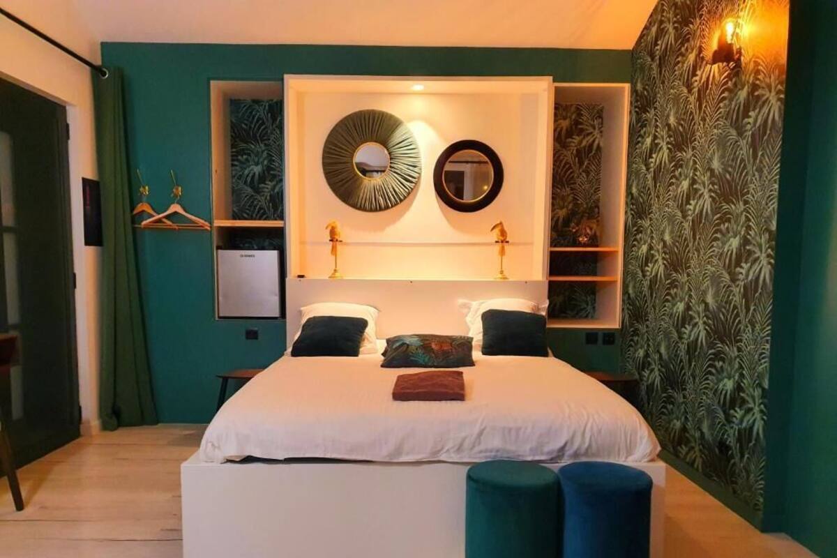 A bedroom with a large bed, two bedside tables, a wardrobe, and a wall-mounted shelf with decorative items.