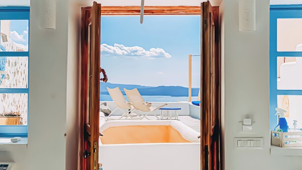 A room with a view of a pool and lounge chairs. - EVERBLUE by Thireon Soothing 2-bedroom villa with AC in peaceful Oia (Oia)