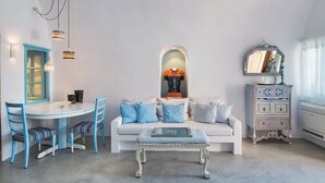 A living room with a white sofa, blue chairs, a coffee table, and a dresser with a mirror. - EVERBLUE by Thireon Soothing 2-bedroom villa with AC in peaceful Oia (Oia)