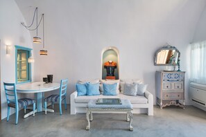 A living room with a white sofa, blue chairs, a coffee table, and a dresser with a mirror. - EVERBLUE by Thireon Soothing 2-bedroom villa with AC in peaceful Oia (Oia)