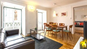 A modern living room with a leather sofa, a glass coffee table, and a dining area with wooden chairs and a table. - C2 Authentic Stay | XVIII Century Charm | DT (Lisboa ciudad)