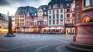Een historisch plein met kinderkopjes, traditionele Europese architectuur en terrassen.