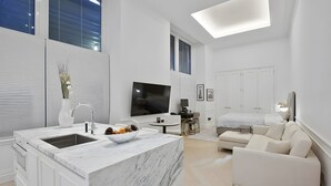 Een moderne woonruimte met een keukeneiland, een bank, een televisie en een eethoek.