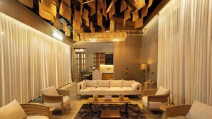 A spacious living room with a sofa, armchairs, a coffee table, and a chandelier.