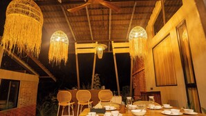 A dining area with a wooden table set for four, surrounded by wicker chairs.