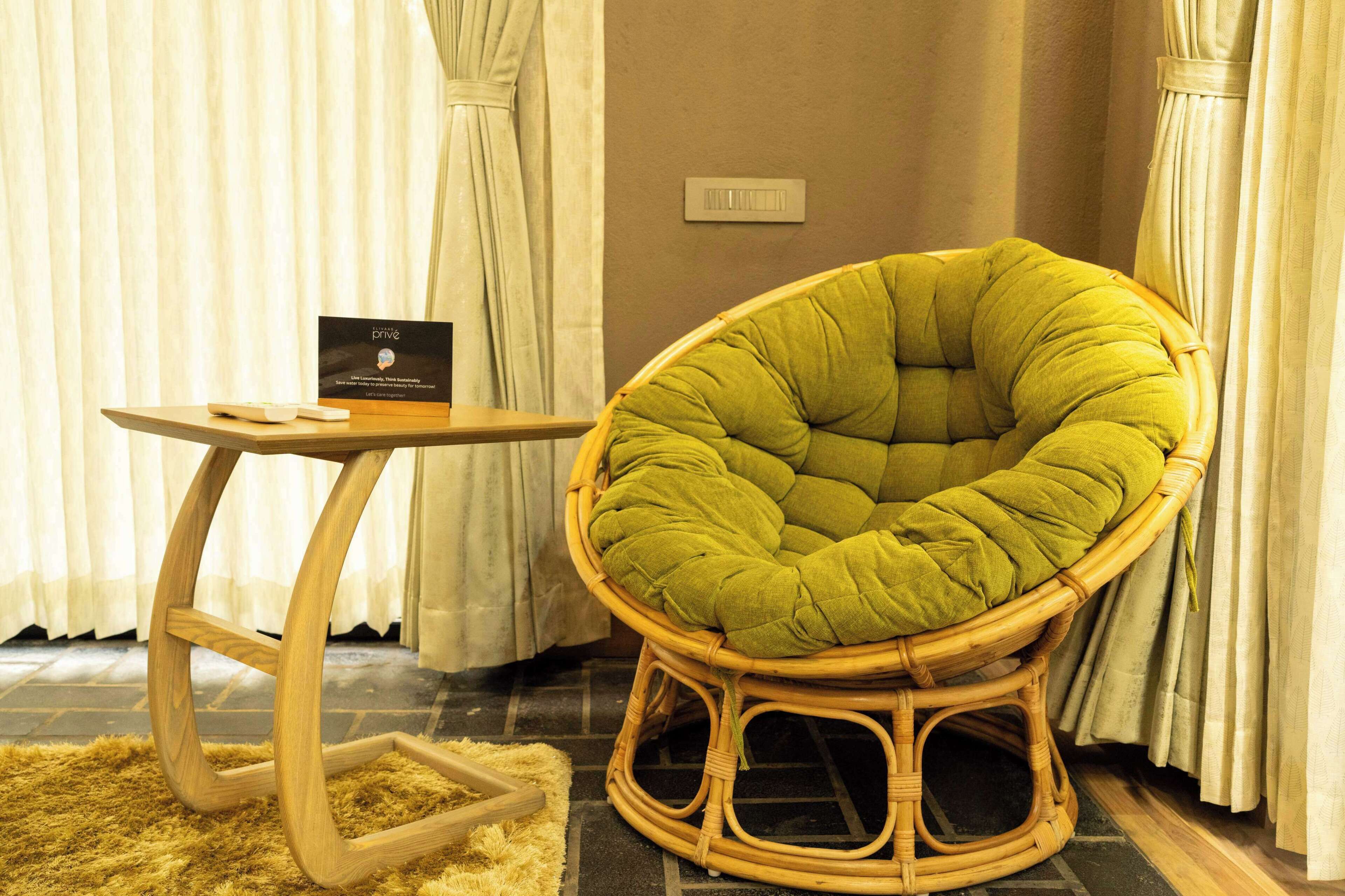 A room with a green cushioned chair, a small wooden table, and a sign on the table.