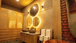 A modern bathroom with wooden cabinets, a large mirror, and a copper bathtub.