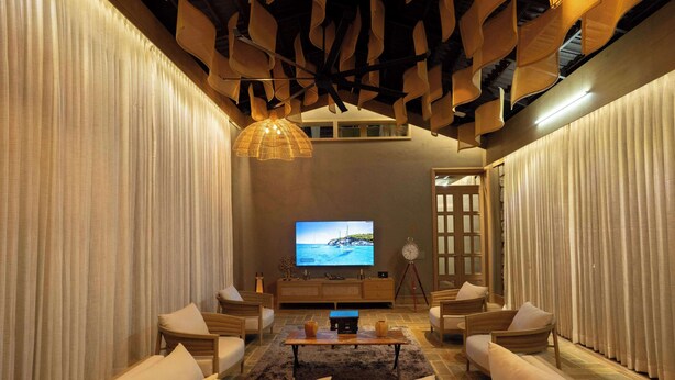 A modern living room with a large flat-screen TV, comfortable seating, and a decorative ceiling.