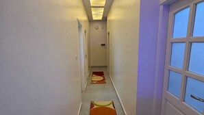 A hallway with a long, colorful rug, a ceiling light fixture, and a window on the right. - BEPY'S NUBAIN HOUSE  (Aswan)