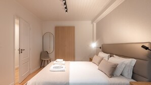 A neatly arranged bedroom with a bed, bedside tables, a mirror, and a wooden wardrobe. - BE Fully Renovated | Central | Private Patio (Lisboa ciudad)