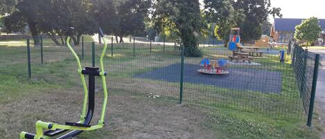 Un parque infantil con equipo de ejercicio, un balancín y columpios.
