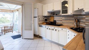 A modern kitchen with white cabinets, a wooden countertop, and a gas stove. - Holiday Home 'L'escale Kénanaise' with Private Garden and Wi-Fi (Saint-Quay-Perros)