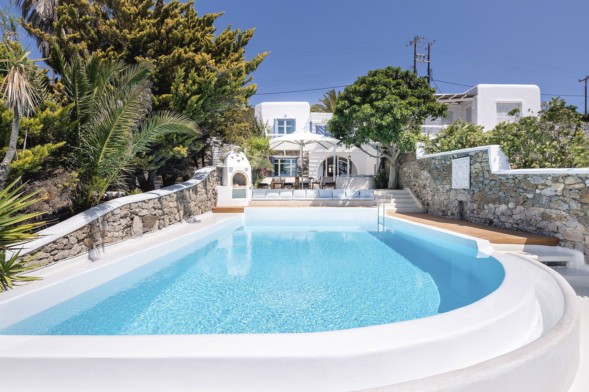 A swimming pool with a stone wall and a white building in the background.