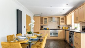 A modern kitchen with wooden cabinets, a stainless steel stove, and a washing machine. - Contractors/family - Parking - Wifi - Sleeps 6 (Milton Keynes)