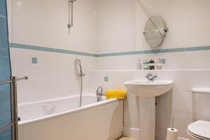 Tina con regadera, tina profunda, toallas 