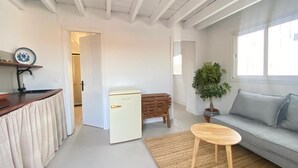 A compact living space with a kitchenette, a small refrigerator, a dining table, a sofa, and a potted plant. - Casa Lola - Rural apartment with private swimming pool in Cabo de Gata (AN)