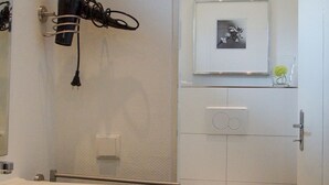 Un bagno con un lavandino bianco, un WC e un quadro appeso al muro.