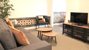 A living room with a sofa, a chair, a small table, a TV, and a plant. - SJ1D Warm & Inviting | Historic Stay! | A/C (Lisboa ciudad)