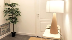 A hallway with a potted plant, a white door, and a table with a lamp. - SJ1D Warm & Inviting | Historic Stay! | A/C (Lisboa ciudad)