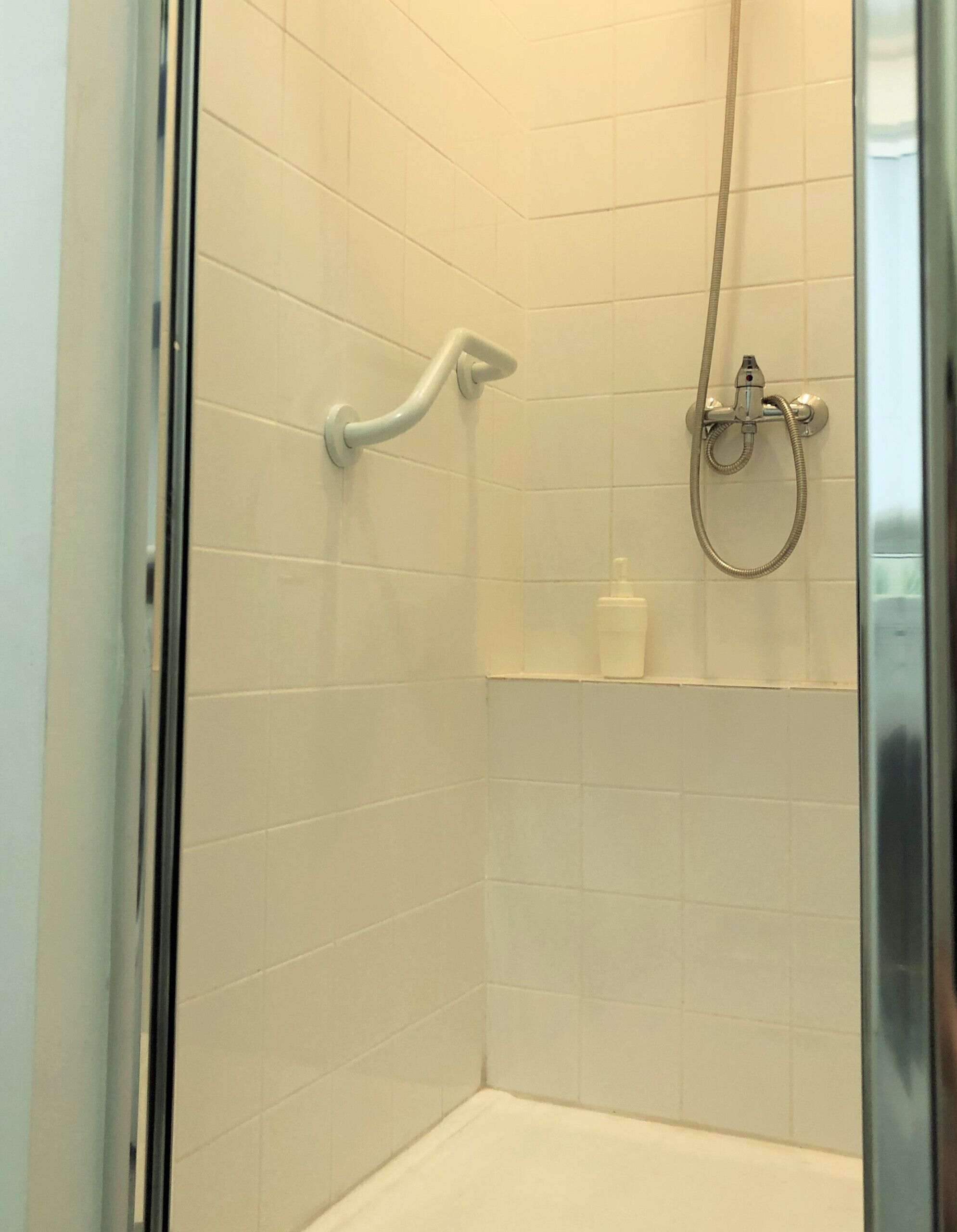 Eine Dusche mit einer Handbrause und einem Handtuchhahn.