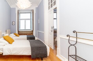 A bedroom with two beds, a window, a door, and a metal rack. - SJ2D Newly Renovated! Cosy & Downtown! | Historic Stay! (Lisboa ciudad)