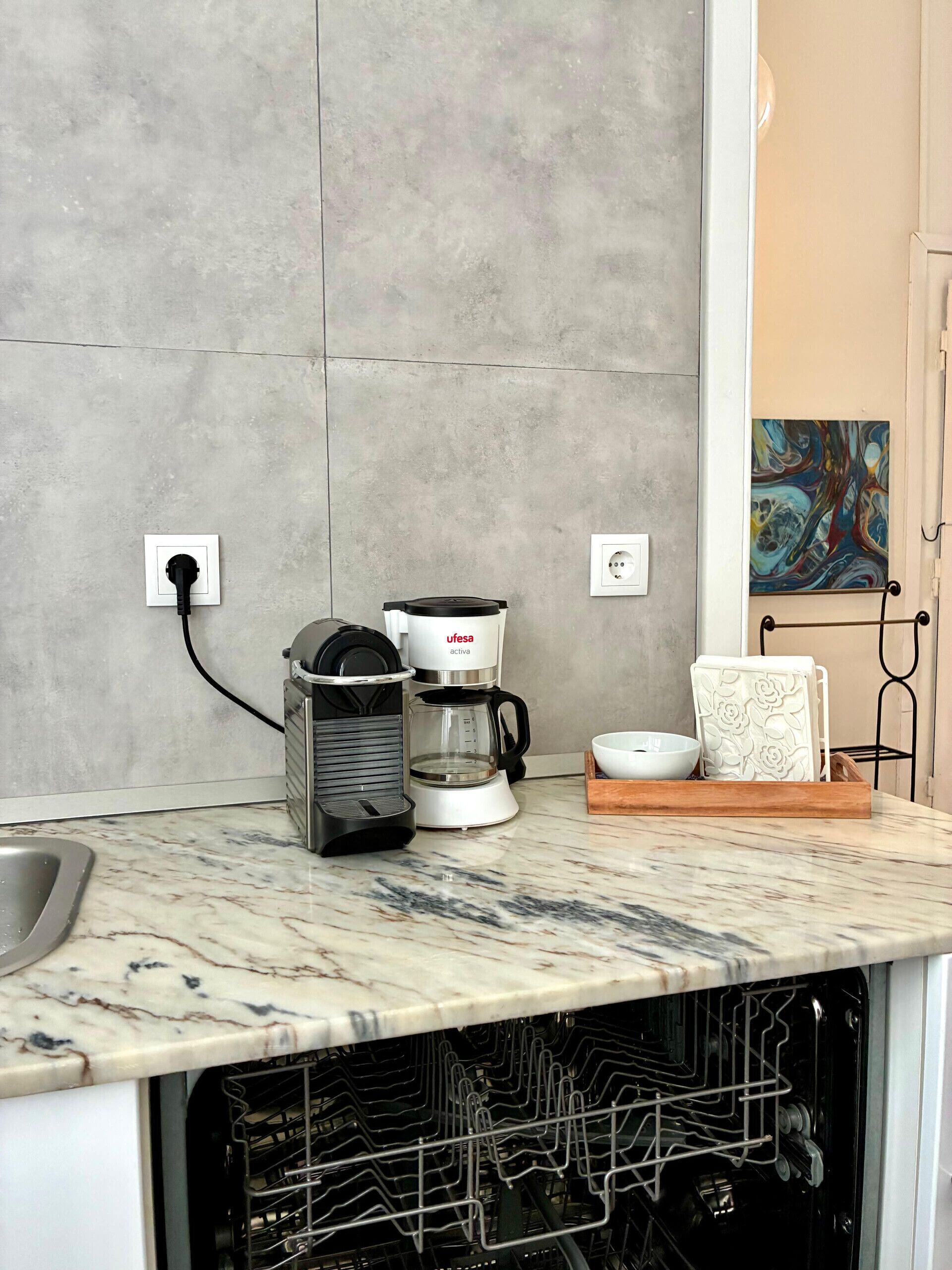 Une cuisine équipée d’une machine à café, d’un égouttoir et d’une prise de courant.