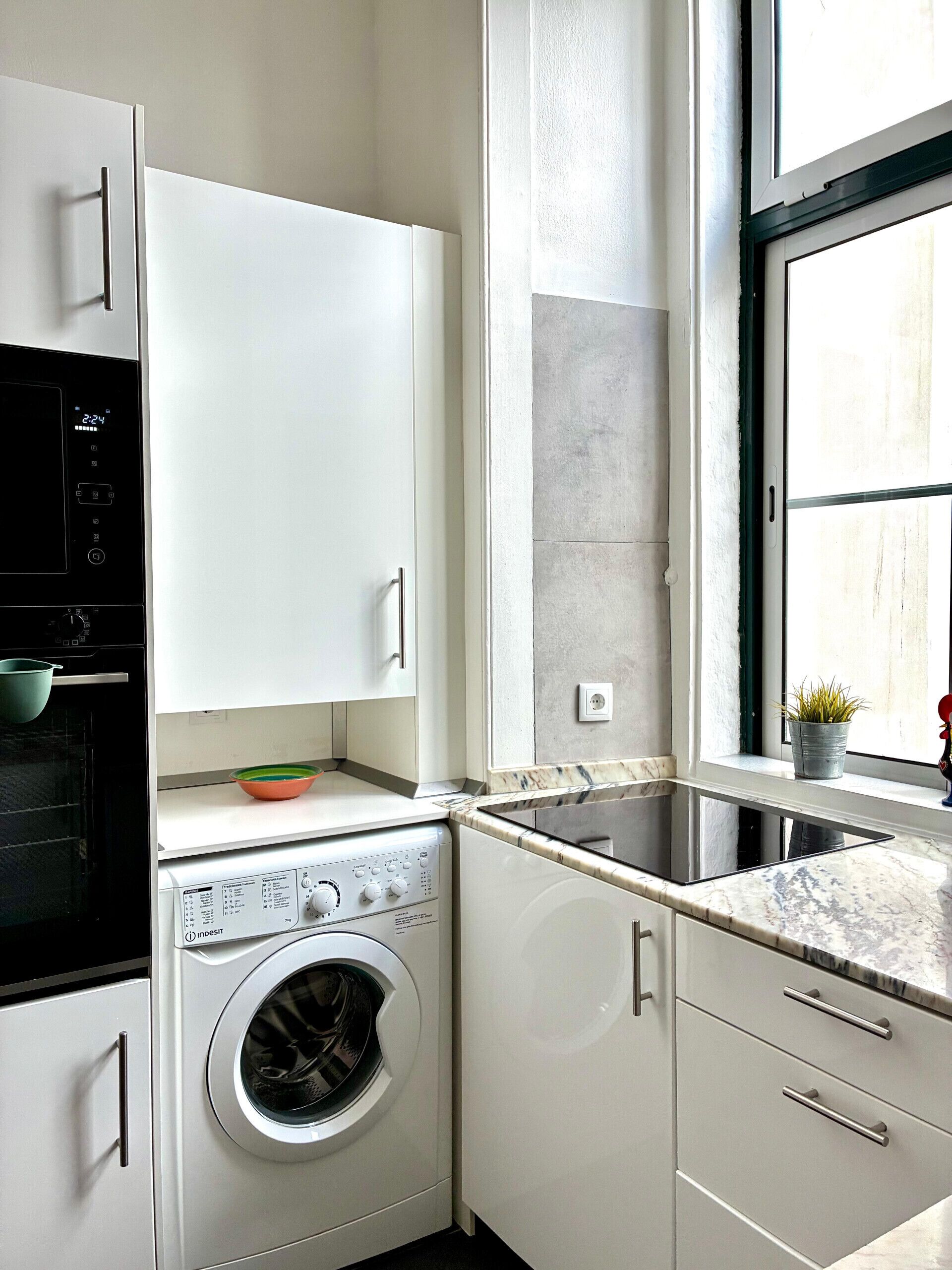 A compact kitchen with a built-in oven, a washing machine, and a sink.