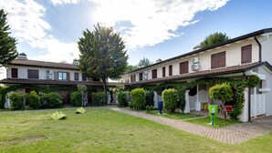 A courtyard with a paved walkway, neatly trimmed hedges, and a large planter. - Apartment 'Borgo Stella X' with Private Terrace, Wi-Fi and Air Conditioning (Bibione)