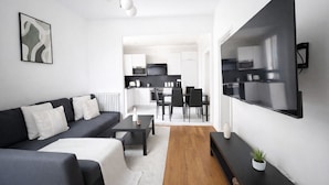 Un salon moderne avec un canapé, une table basse et un téléviseur fixé au mur.