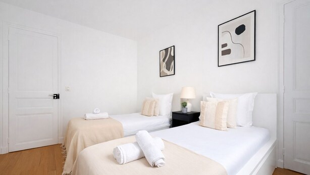 Ein Hotelzimmer mit zwei Betten, einem Nachttisch und zwei gerahmten Kunstwerken an der Wand.