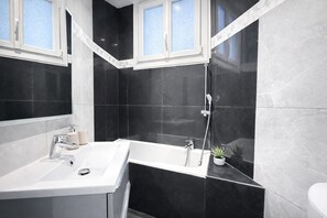 Un baño moderno con lavamanos blanco, bañera y ducha.