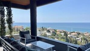 A balcony with a view of the sea, furnished with a sofa and chairs, and a small table. - Kfaraabida SKY (Batroun)