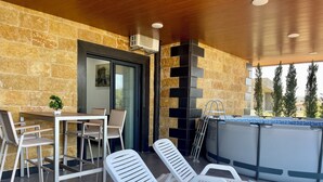 A modern outdoor lounge area with stone walls, a pool table, and lounge chairs. - Kfaraabida SKY (Batroun)