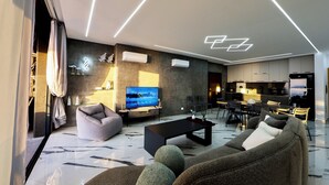 A modern living room with a flat-screen TV, a sofa, a coffee table, and a dining area with chairs. - Kfaraabida SKY (Batroun)
