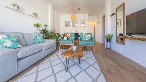 Een moderne woonkamer met een bank, twee fauteuils, een salontafel en een grote spiegel.