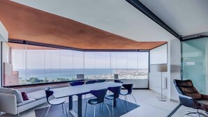 Una habitación moderna con una mesa grande, sillas, un sofá y vistas a la ciudad.