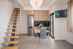 A modern kitchen with a built-in refrigerator, wooden cabinets, and a dining area with a table and chairs. - Sea View Frini - Lefkada Fully Equipped Getaway (Frini)