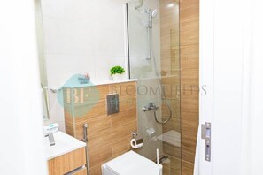 A modern bathroom with a shower, a toilet, and a sink. - Bloomfields Iconic 1BR in Oasis Masd (Abu Dhabi)