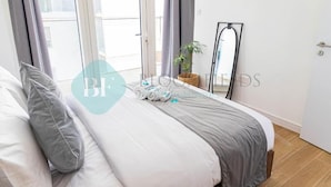A bedroom with a bed, pillows, a plant, and a mirror. - Bloomfields Iconic 1BR in Oasis Masd (Abu Dhabi)