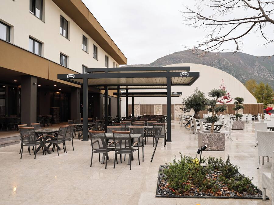 An outdoor patio with tables and chairs, a covered seating area, and a mountainous backdrop.
