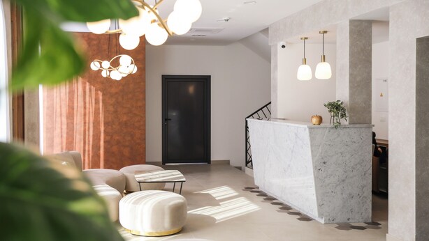 A modern living room with a marble reception desk, a staircase, and a large window with curtains. - Hotel Karting (Mostar)