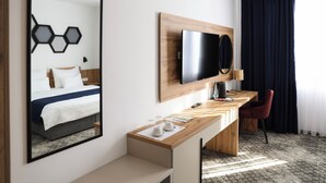 A hotel room with a bed, a desk, a chair, a TV, and a large mirror. - Hotel Karting (Mostar)