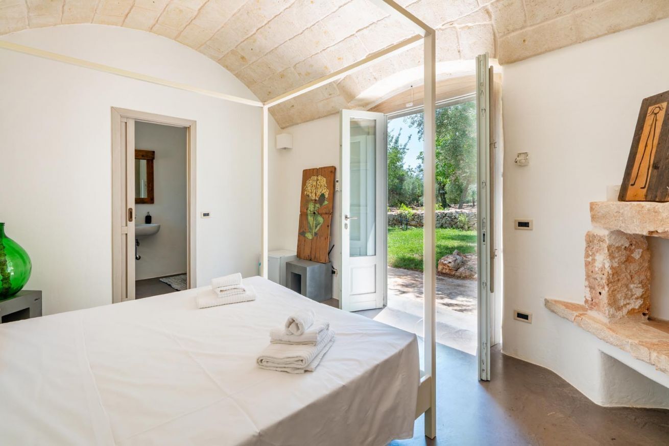 A bedroom with a bed, a bathroom, and a view of the outdoors.