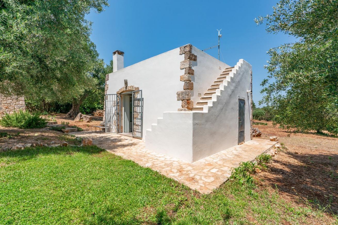 Un petit bâtiment blanc, doté d’un escalier en pierre et d’une grille en métal.